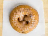 A glazed blueberry cake donut on white paper.