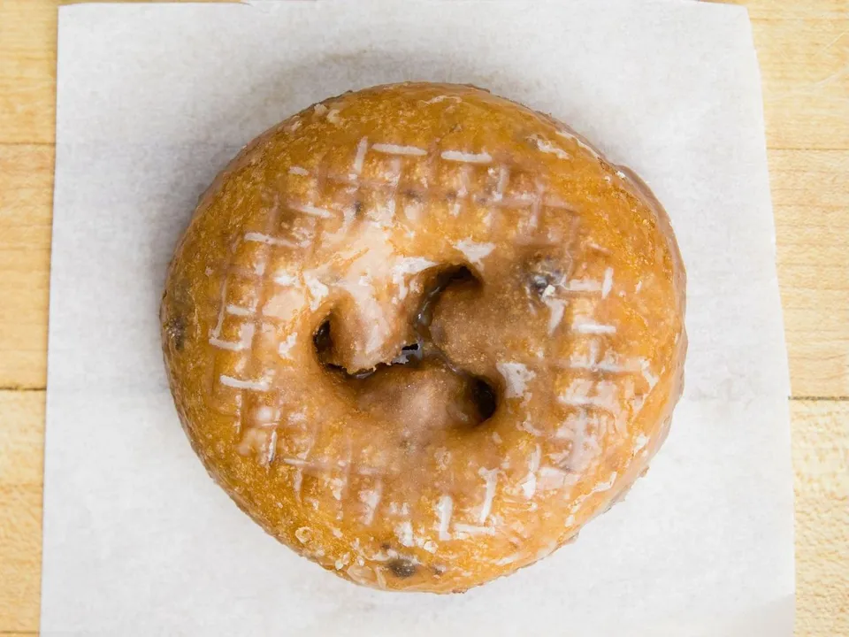 A glazed blueberry cake donut on white paper.
