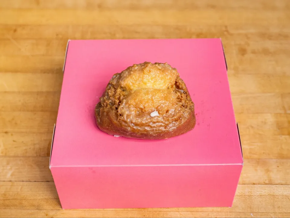 A glazed buttermilk donut on a pink box.