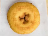 A plain cake donut on white paper.