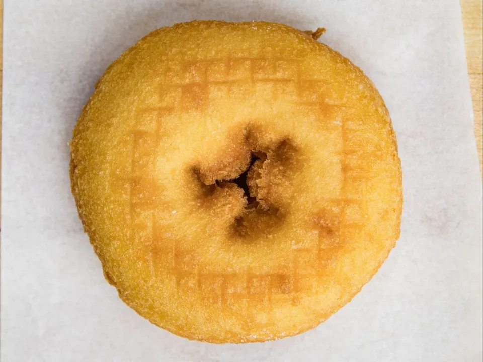 A plain cake donut on white paper.