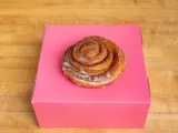 A glazed cinnamon roll on a pink box.