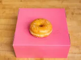 A glazed donut on a pink box.
