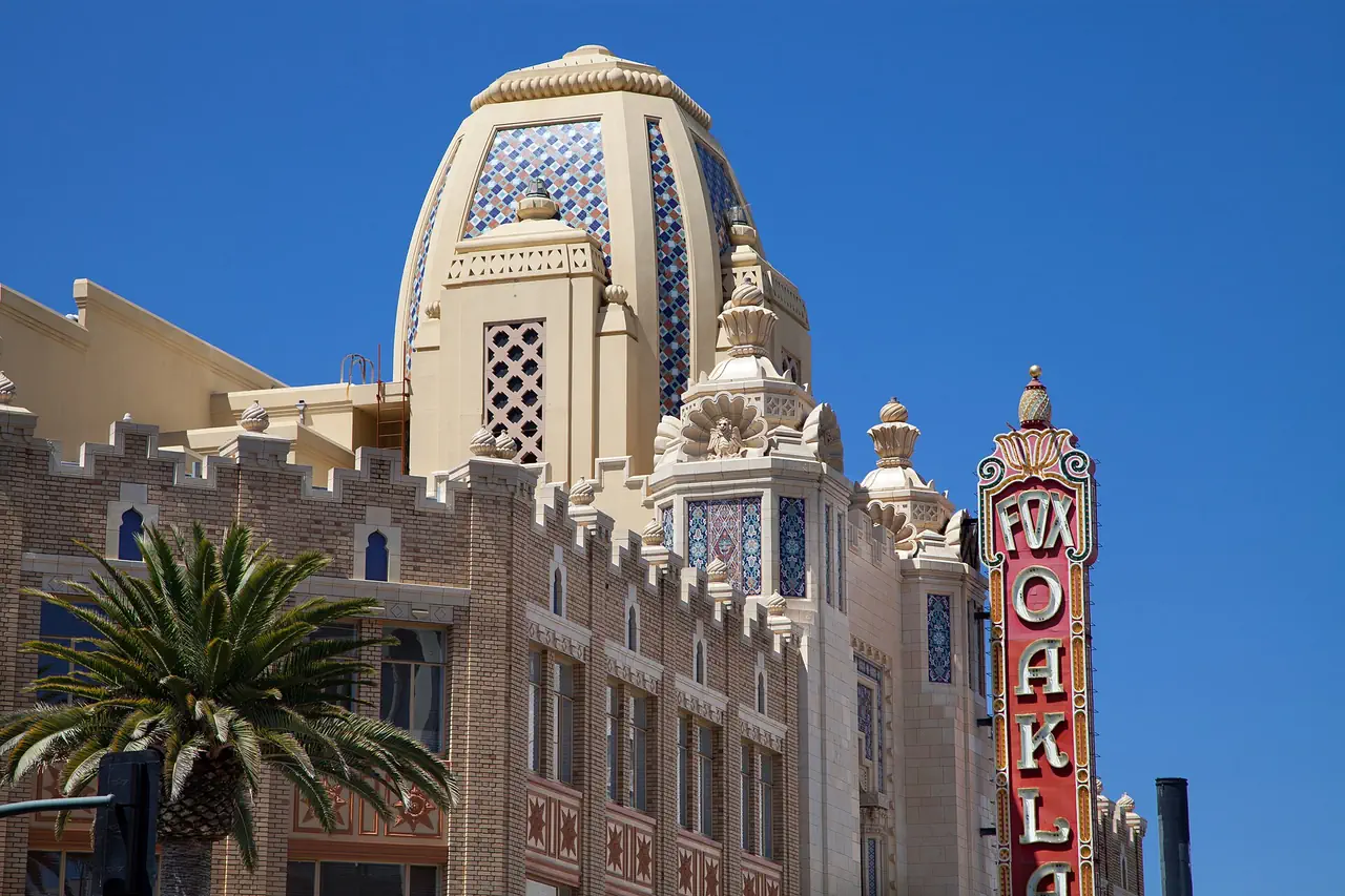 Close view of the Fox Oakland Theatre's patterned tile dome, ornate towers and red FOX OAKLAND sign against a deep blue sky.