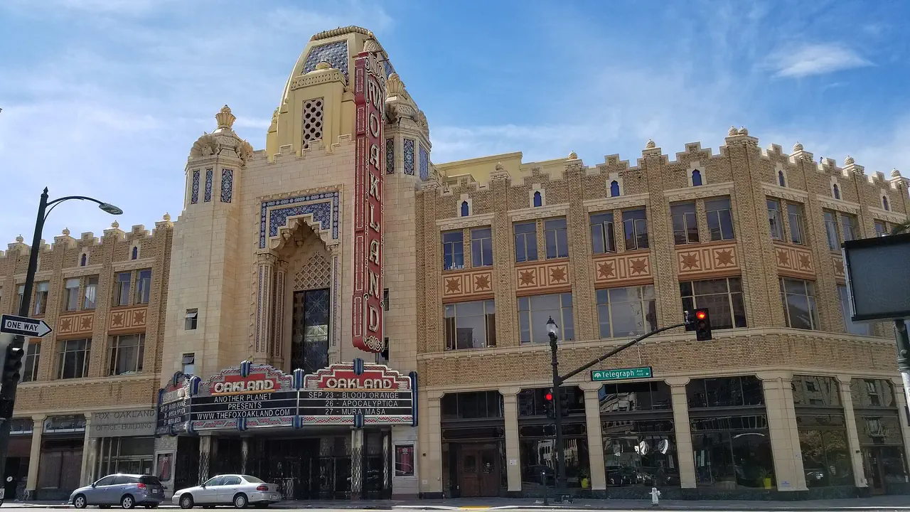 The front of the Fox Oakland Theatre in Uptown Oakland, with its OAKLAND marquee, tall vertical sign and tiled tower above the entrance.