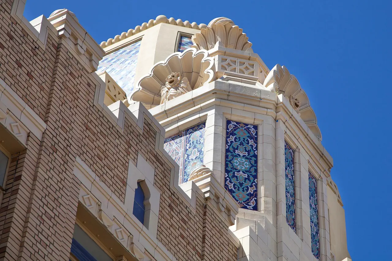 Blue and turquoise tile panels and a carved shell ornament on a tower of the Fox Oakland Theatre, Oakland, against a blue sky.
