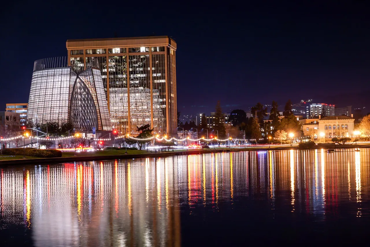 The Necklace of Lights along the shore of Lake Merritt, Oakland, at night, with the Cathedral of Christ the Light and a lit tower reflected in the water.