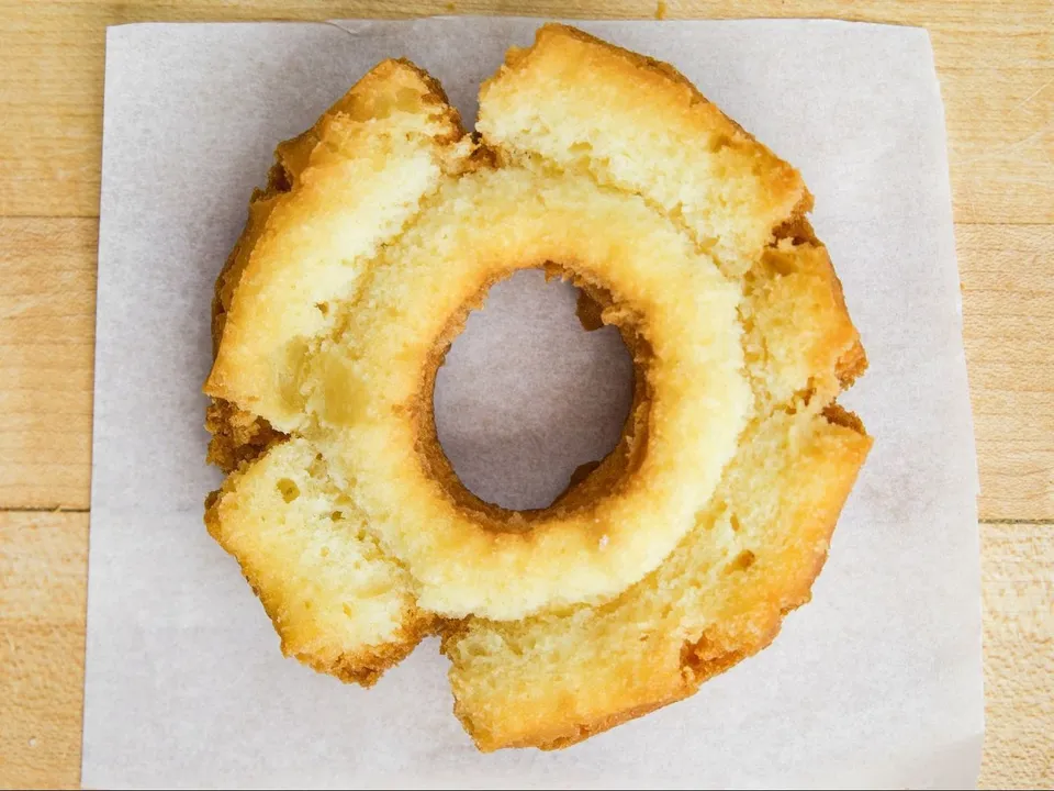 A plain old fashioned donut on white paper.