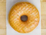 A glazed raised donut on white paper.