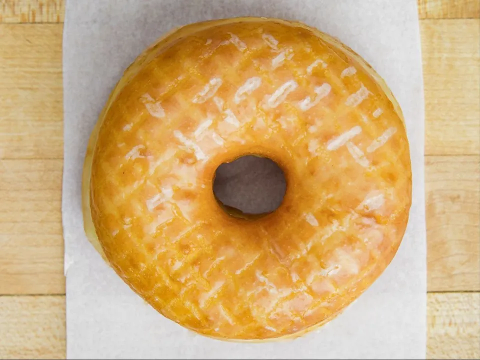 A glazed raised donut on white paper.